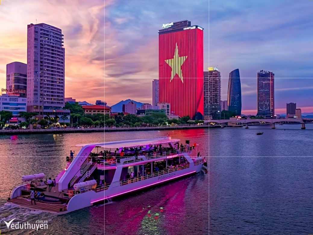 Du thuyền Poseidon Cruise lung linh trên sông Hàn Đà Nẵng, cùng cảnh hoàng hôn tuyệt đẹp và tòa nhà được chiếu sáng ấn tượng.